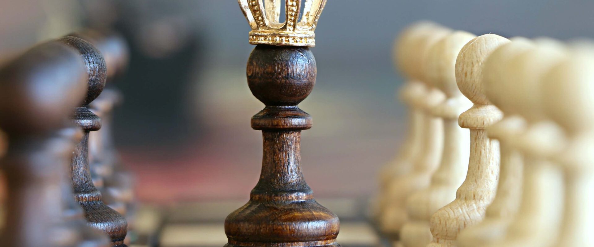 Figura czarnego króla na środku szachownicy. Z prawej strony są białe pionki, z lewej strony są czarne pionki