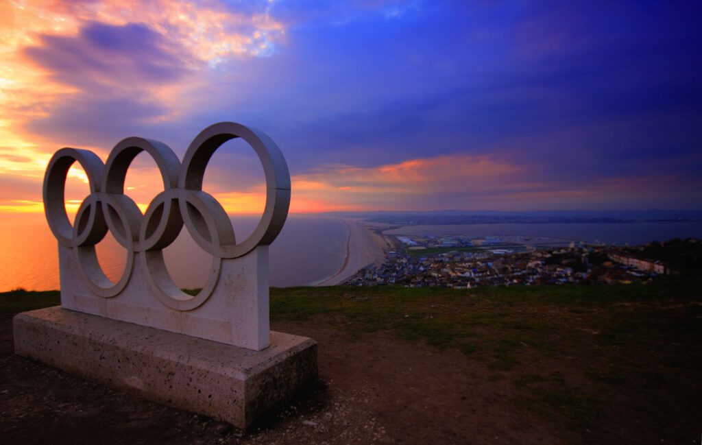 Pomnik z symbolem olimpijskim na wzgórzu. W tle widać miasto