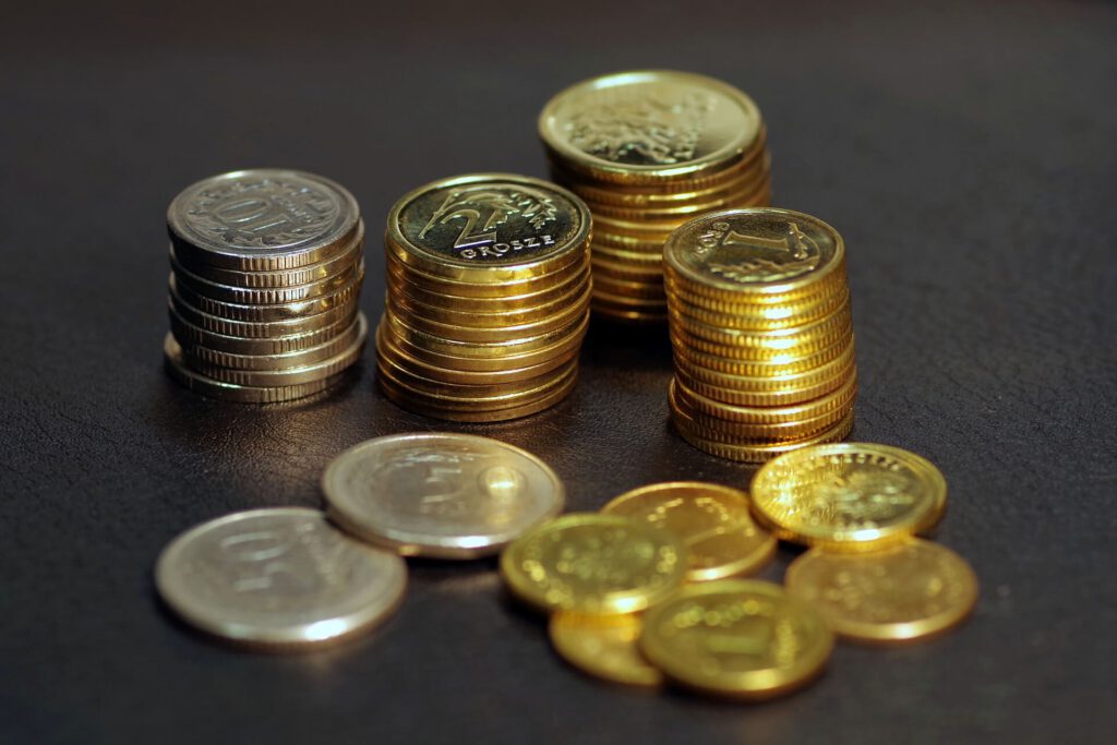 Stosy monet z polskimi groszami o różnej wartości stojące na ciemnej powierzchni 