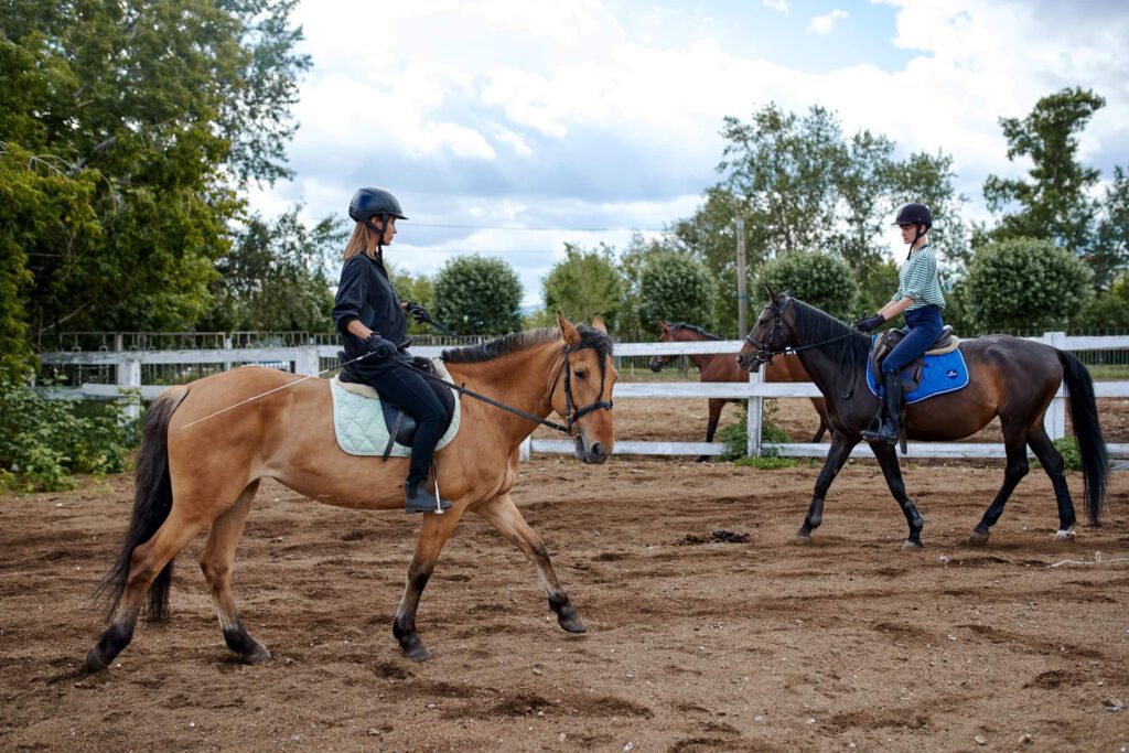 Dwie dziewczyny podczas treningu jeździeckiego siedzą na koniach. Trening jeździecki również może podlegać zwolnieniu z VAT.